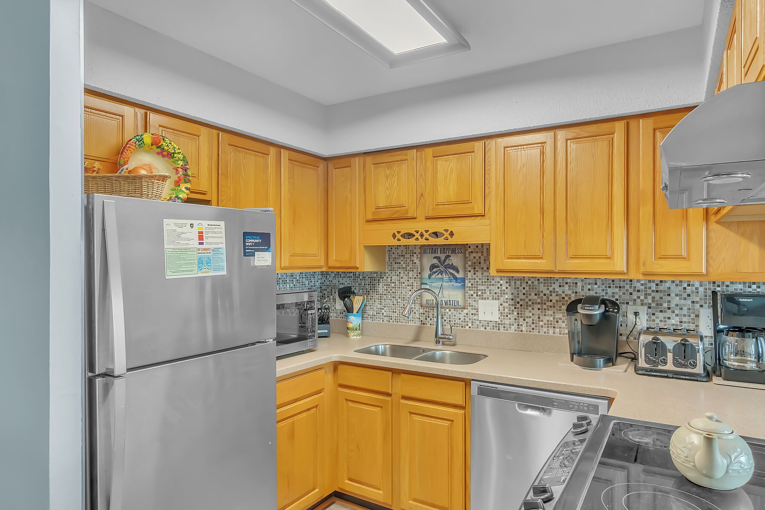 A modern kitchen with wooden cabinets, stainless steel appliances, and a tiled backsplash.