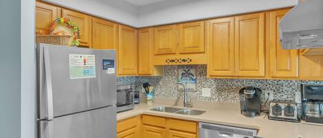 A modern kitchen with wooden cabinets, stainless steel appliances, and a tiled backsplash.