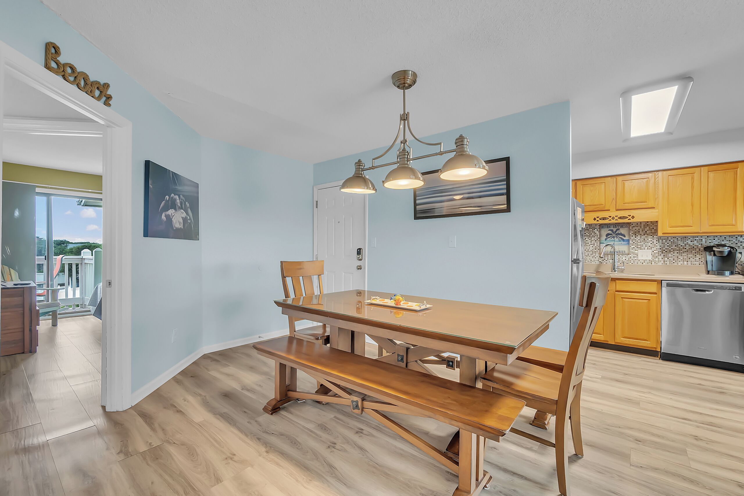 A modern kitchen with wooden cabinets, a dining table, and a bench.