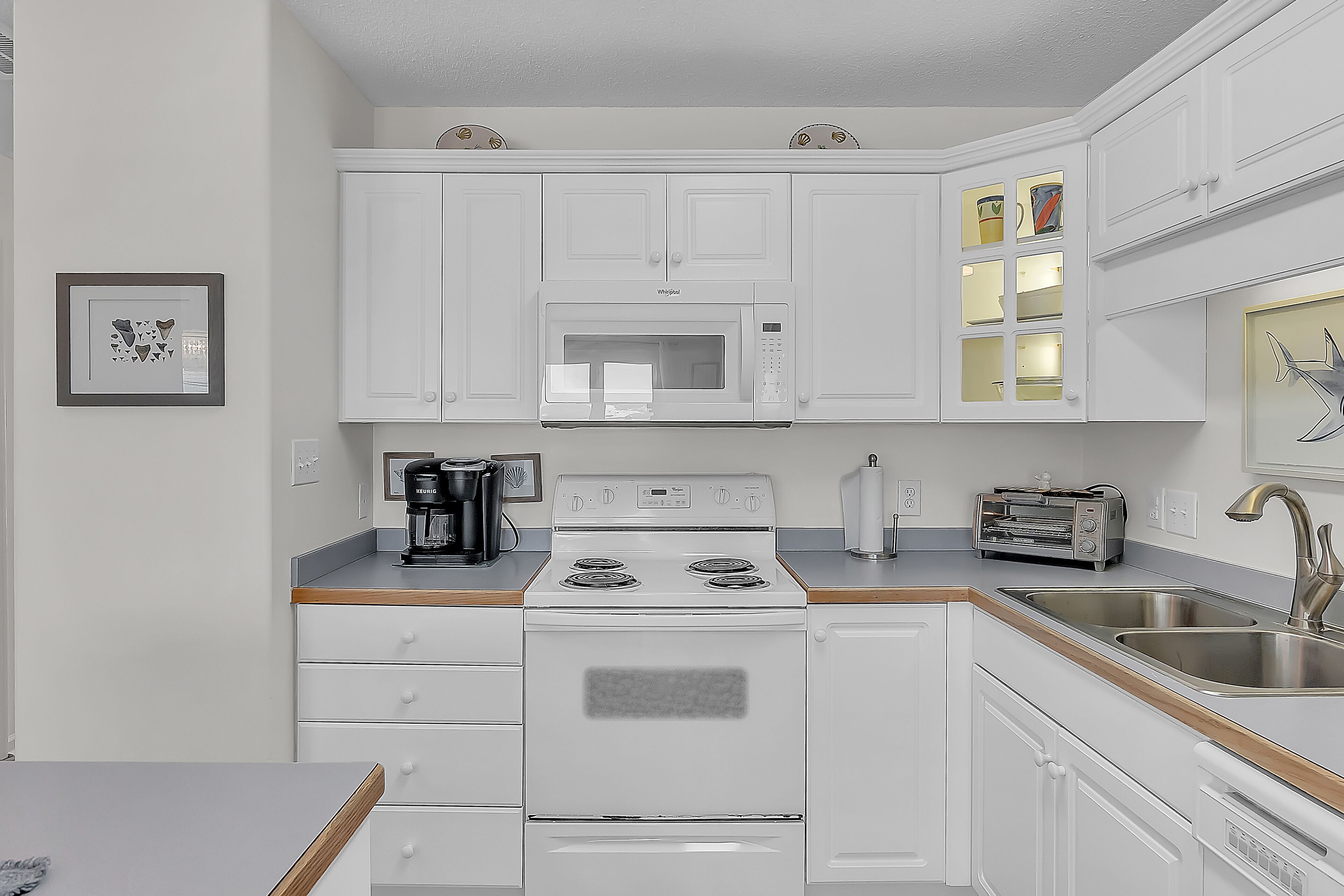 A modern kitchen with white cabinets, a microwave, a stove, and a sink.