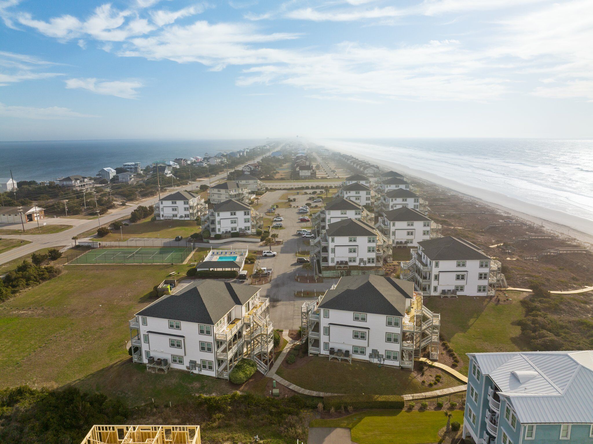 A coastal residential area with multiple-story houses, a beach, and a clear view of the ocean.