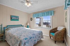 A bedroom with a bed, a chair, a window with a view, and a ceiling fan. - 4BR, Ocean Front, Dogs OK - One Level! (Emerald Isle)