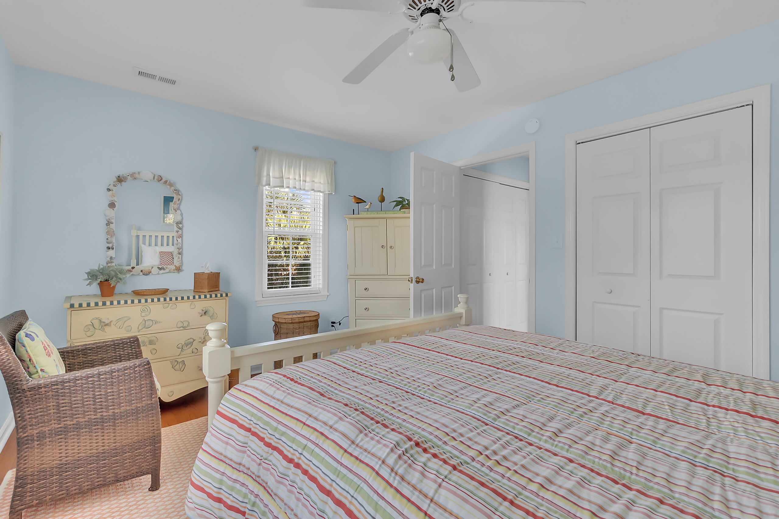 Relax in your peaceful blue bedroom with coastal decor, cozy seating, and gentle ceiling fan breeze for perfect comfort.