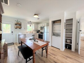Una cocina con armarios blancos, una mesa de madera y un horno empotrado.