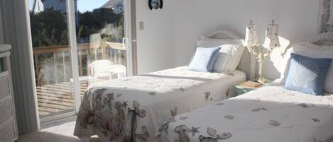 A bedroom with two beds, a balcony, and a white wall.