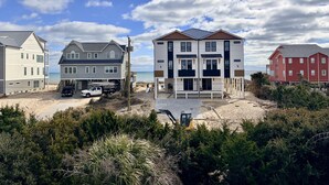 A beachfront property with multiple houses, a sandy beach, and a clear sky. - POOL & DOGS WELCOME! Easy Beach Access (Emerald Isle)
