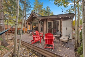 A cabin with a deck, outdoor seating, and a large window.