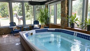 A hot tub with a 3 ft depth, surrounded by wooden decking, stone walls, and potted plants.