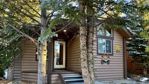 A cabin with a front door, a Jeep Trail sign, and a small porch with steps.
