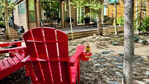 A log cabin with a porch, outdoor seating, and a bottle of wine on a chair.