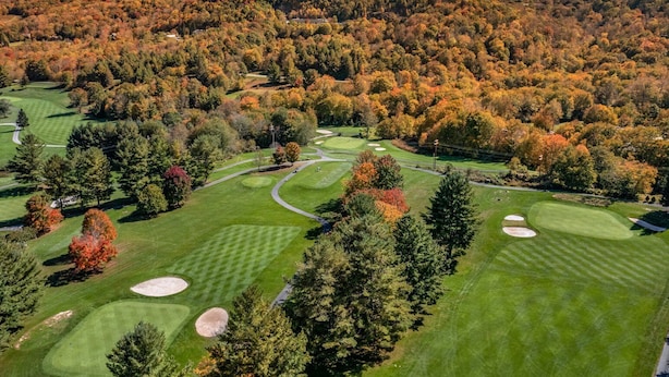 En golfbane med et bjergrigt baggrundslandskab og efterårsfarver.