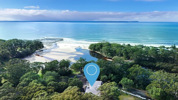 Une vue aérienne d’une zone côtière, avec une plage, une végétation luxuriante et un ciel bleu dégagé.