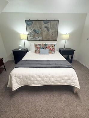 A bedroom with a large bed, two nightstands, two lamps, a wall art piece, and a carpeted floor. - Forever Family Farm Hunters Welcome Mountain Views (Montrose)