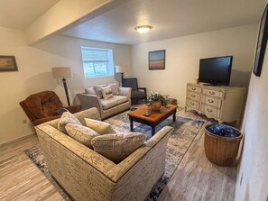 A living room with a sofa, armchairs, a coffee table, a television, and a decorative basket. - Forever Family Farm Hunters Welcome Mountain Views (Montrose)