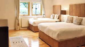 A hotel room with two beds, a radiator, a window with curtains, and a bedside table with a lamp. - Family Lodge No. 2 The Place Downstairs - UK45691 (Pitlochry)