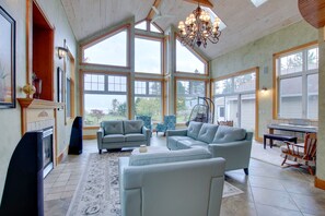 Amplia sala de estar con ventanas grandes, chimenea y candelabro.