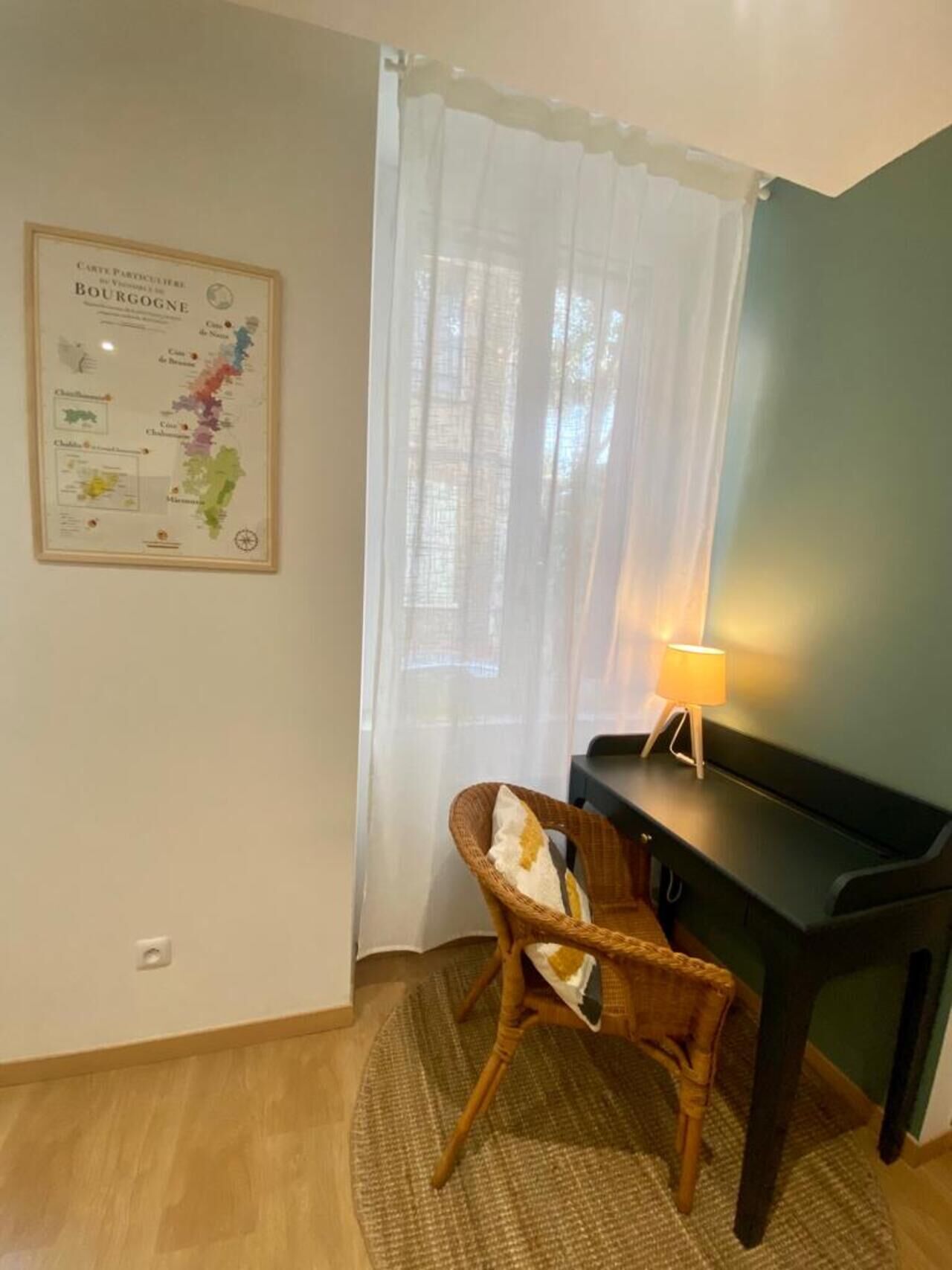 Une pièce avec un piano, un fauteuil en osier, une lampe et une carte accrochée au mur.