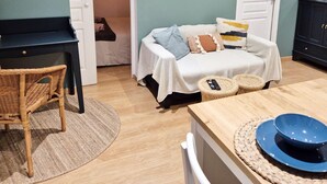 Une pièce confortable avec un lit, une chaise en osier, une table en bois et un buffet.