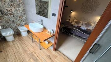 A modern bathroom with a wooden vanity, a large mirror, and a shower area.
