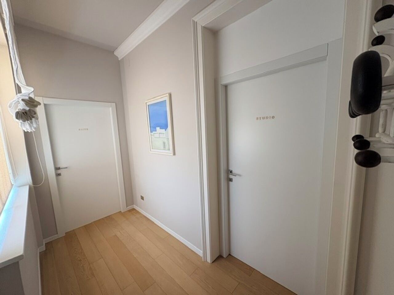 A hallway with wooden flooring, white walls, and doors with 'STUDIO' signage.