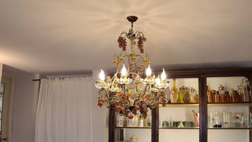 A dining table with a variety of fruits and a chandelier above.