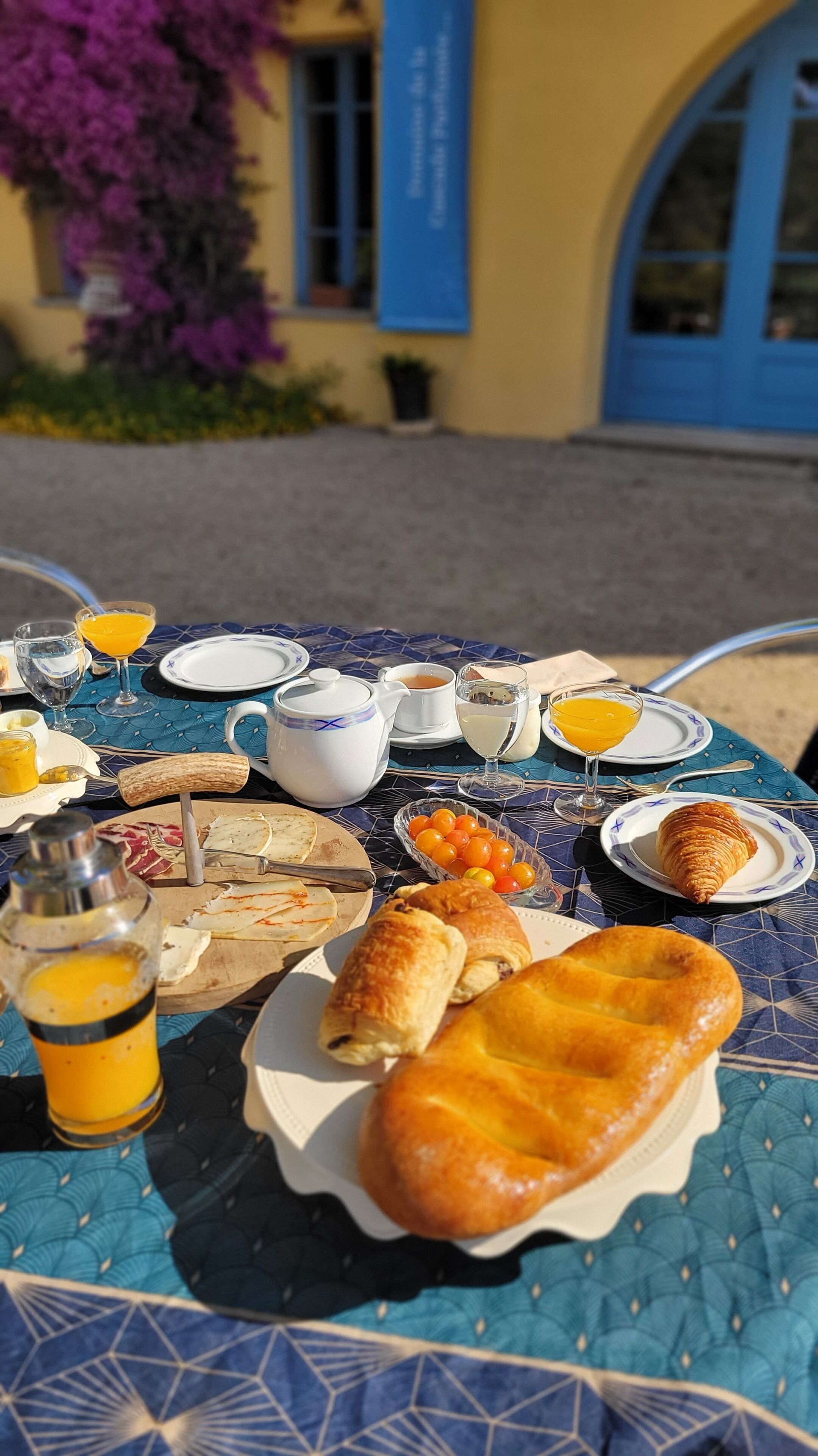 Una mesa dispuesta para el desayuno con cruasanes, zumo de naranja y una tetera.