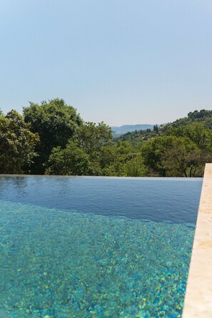 A clear swimming pool with a view of lush greenery and distant hills. - Domaine de la Cascade Parfumée (Grasse)