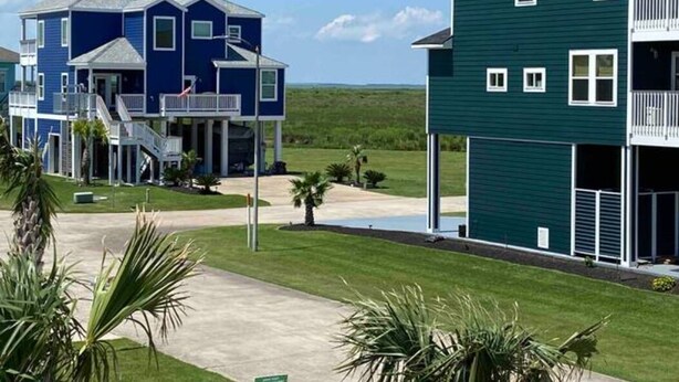 A residential area with two houses, one blue and one green, featuring balconies and a well-maintained lawn. - The Blue Crab (Galveston)