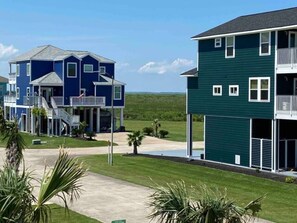 A residential area with two houses, one blue and one green, featuring balconies and a well-maintained lawn. - The Blue Crab (Galveston)