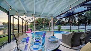 A covered outdoor area with a pool, seating, and dining setup.