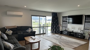 Ein modernes Wohnzimmer mit einer Eckcouch, einem Couchtisch, einem Fernseher und einem Balkon mit Blick.