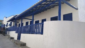 Ein Gebäude mit weißer Fassade und blauen Akzenten, darunter ein Balkon mit blauen Geländern und eine blaue Tür.