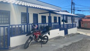 Ein Gebäude mit weißer Fassade und blauen Akzenten, davor ein geparktes Motorrad und ein klarer, blauer Himmel.