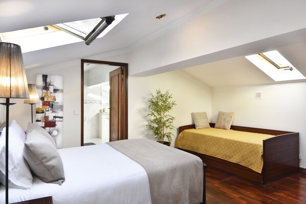 Un dormitorio con cama, mesita de noche, lámpara y tragaluz.
