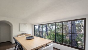 Ein moderner Essbereich mit großem Fenster, einem Holztisch und einem weißen Stuhl.