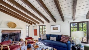 Ein gemütliches Wohnzimmer mit Kamin, einem blauen Sofa und Holzbalken an der Decke.