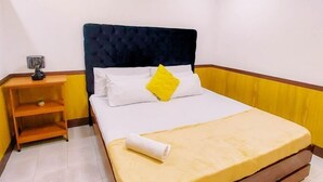 Een hotelkamer met een bed, een nachtkastje en een lamp.