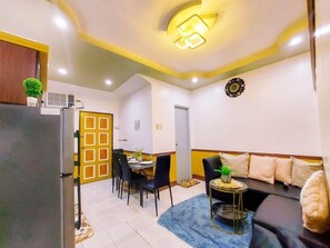 Un espace de vie compact comprenant un coin repas, un canapé et une petite table décorée d’un ananas.