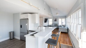 Une cuisine moderne dotée d’un îlot central, d’appareils électroménagers en acier inoxydable et d’un coin bar avec des tabourets.