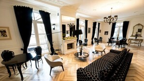 A spacious living room with a fireplace, a large sofa, and a dining area with a table and chairs. - Arté Boutique Hotel (Tirana)
