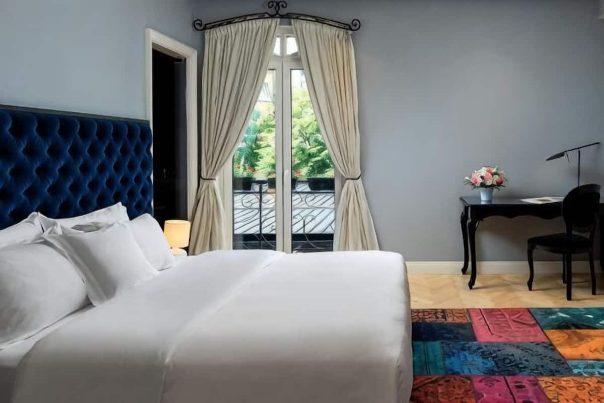 Habitación de hotel con cama, escritorio, silla y vistas al exterior.