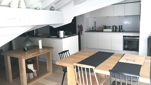 A modern kitchen with white cabinets, a wooden dining table, and a black and white rug.