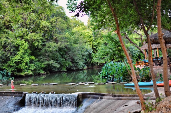 Eine natürliche Umgebung mit Wasserfall, Teich und einem Gebäude mit Strohdach.