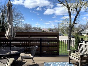 A deck with outdoor furniture, including a table and chairs, and a wooden bench.
