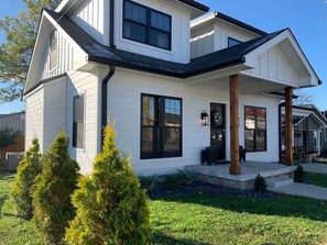 A two-story house with a front porch, large windows, and a well-maintained lawn.