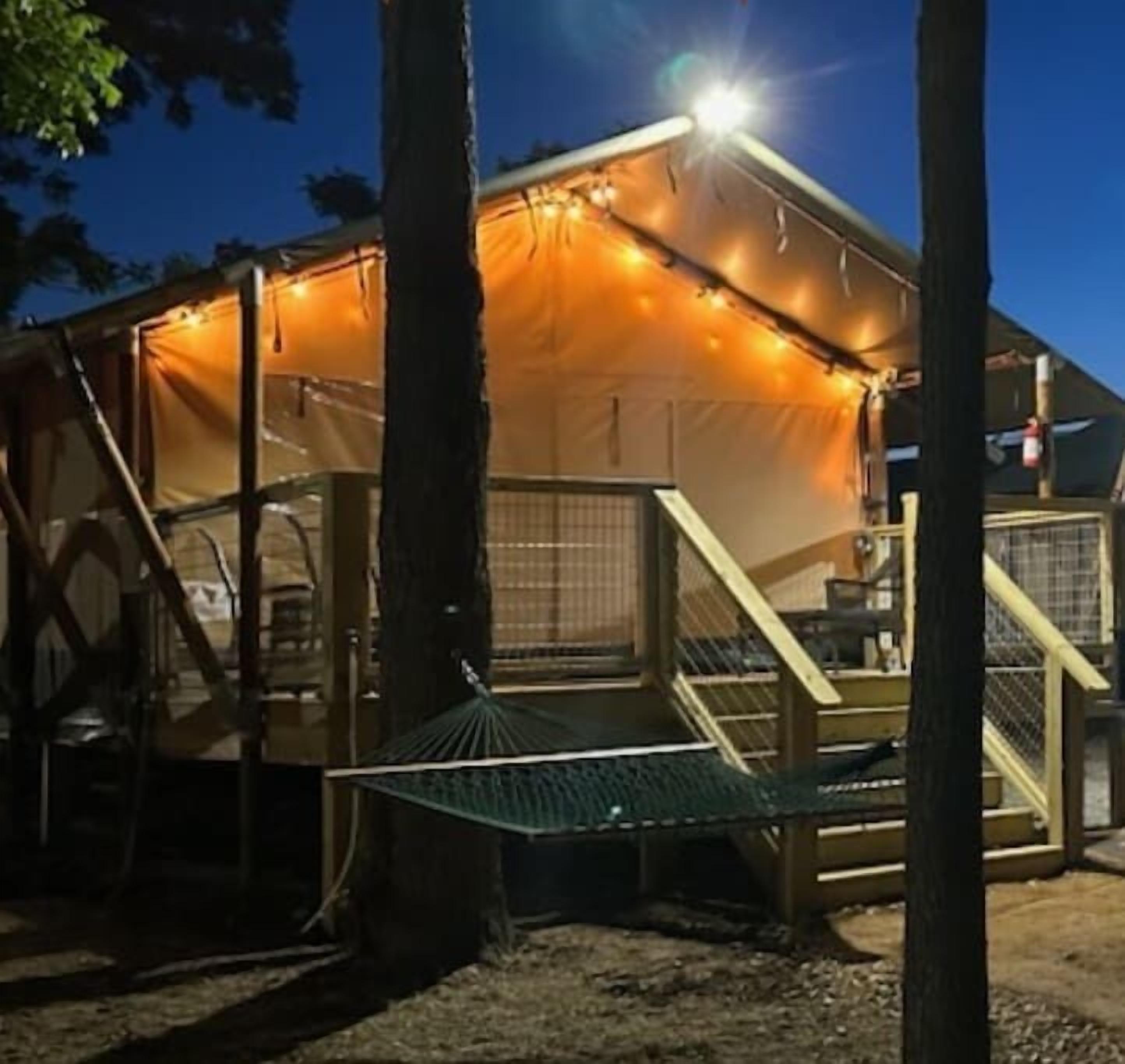 A tent with a ramp and a small platform, surrounded by trees.