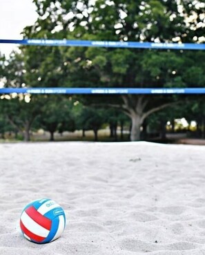 A volleyball on a sandy surface with blue tape and trees in the background. - #23Son’s Rio Cibolo Deluxe Safari Cabin (Marion)