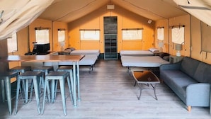 A tented accommodation with a central sleeping area, a dining table with chairs, and a sofa. - #43 Sons River Ranch Safari Cabin (Kingsbury)