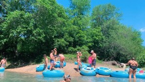 A group of people on inflatable tubes in a natural water setting surrounded by trees. - #47Sons River Ranch Safari Cabin (Kingsbury)