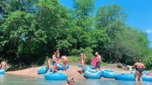 A group of people in a natural setting with trees and a body of water. - #49 Son's River Ranch Safari Cabin (Guadalupe County)